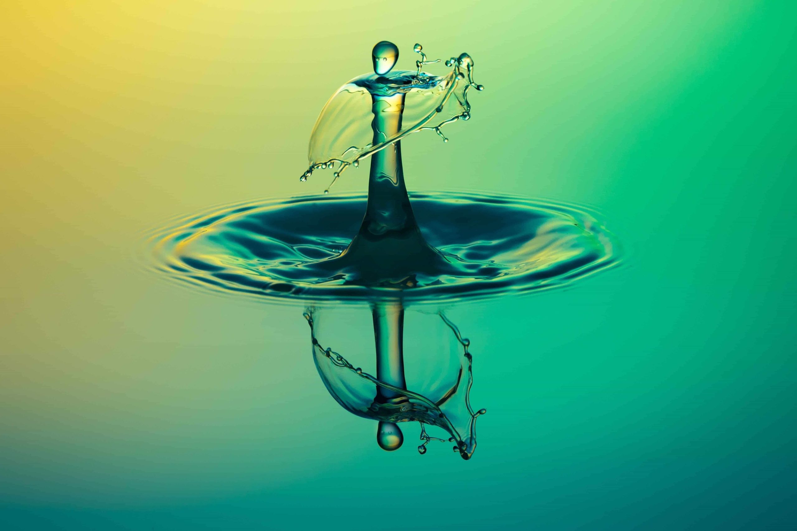 Water droplet forming a human silhouette with its reflection against a yellow and green gradient background.